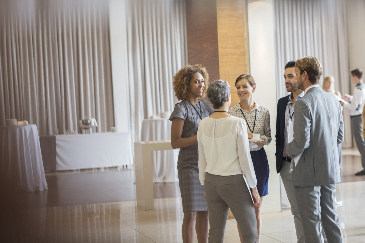 Business people standing in conference room, talking and smiling